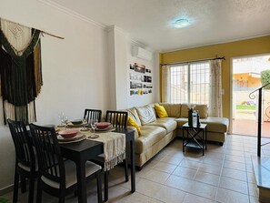 Ein Wohnzimmer mit einer Couch, einem Esstisch mit Stühlen und einem kleinen Beistelltisch.