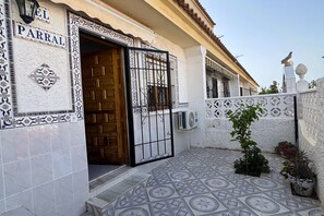 A building entrance with a wooden door, a metal gate, and a tiled patio area. - Casa Margarita by Rental Hero (Alcazares, Los)