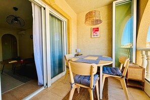 Ein Balkon mit Tisch und Stühlen, einer Korblampe und einem gerahmten Bild an der Wand.