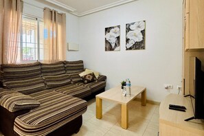 Un salon avec un canapé à rayures, une table basse et deux tableaux accrochés au mur.