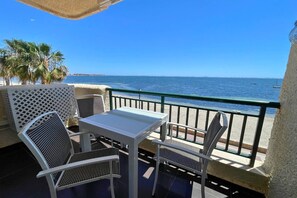 A balcony with a table and chairs, overlooking a beach and the sea. - Casa Paradis by Rental Hero (Alcazares, Los)