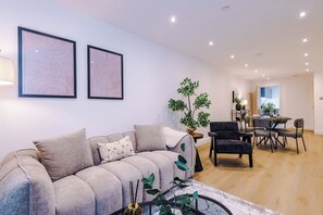 A modern living room with a sofa, chairs, a dining table, and two framed artworks on the wall. - Sleek City Stay 2 Bed Apt Free Parking and Terrace (West Yorkshire)