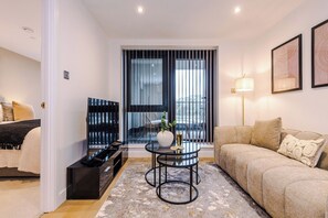 A modern living room with a sofa, a coffee table, and a TV. - Sleek City Stay 2 Bed Apt Free Parking and Terrace (West Yorkshire)