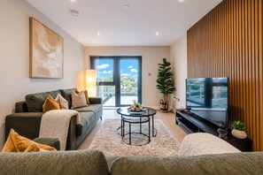 Una sala moderna con sofá, mesa de centro y televisor.