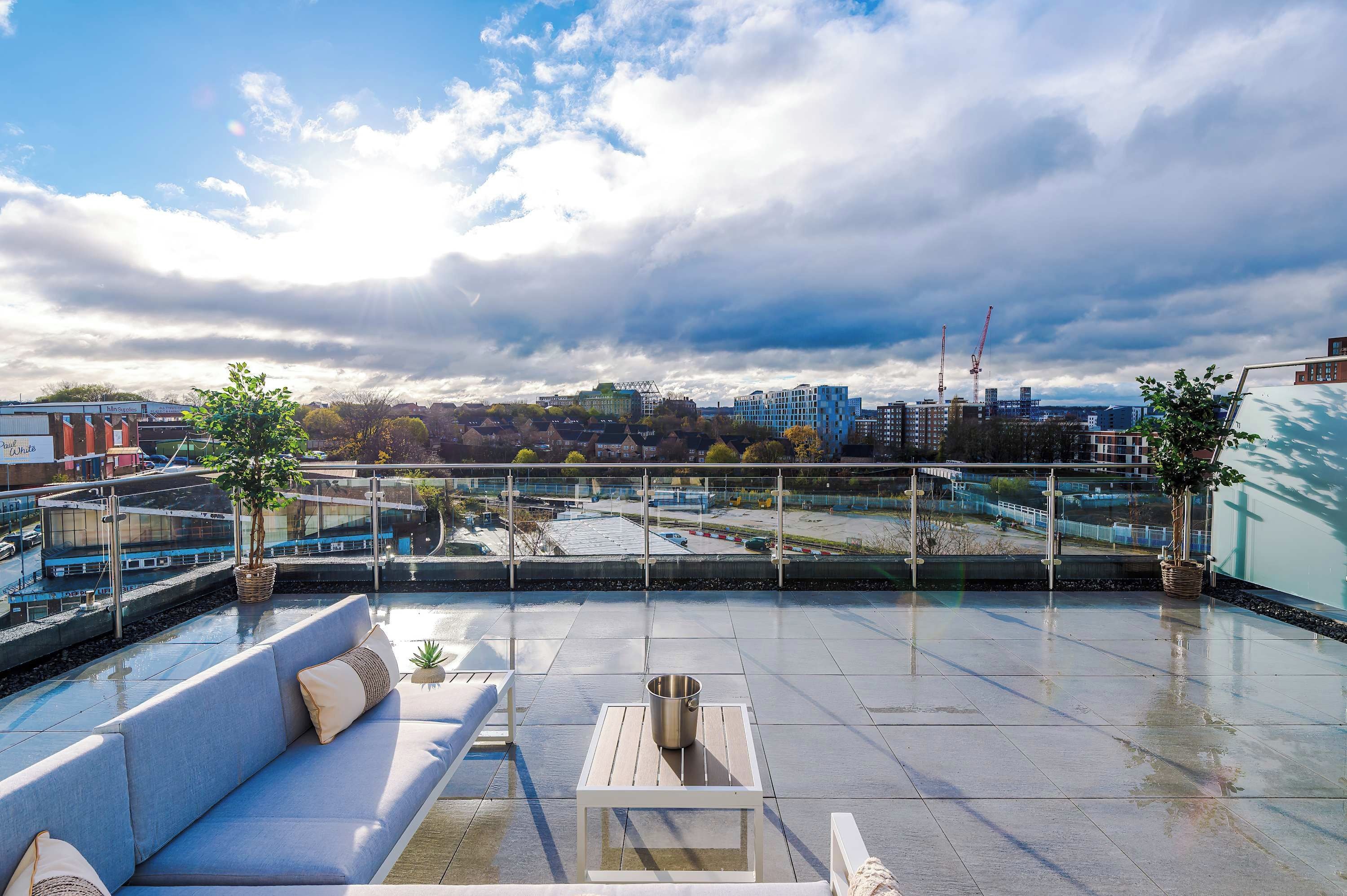 Una terraza en la azotea con vistas al horizonte urbano, una zona de estar con mesa y una barandilla.