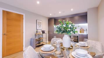 Un comedor moderno con una mesa de vidrio, platos blancos y un jarrón con plantas verdes.