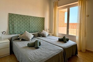 A double bed with a patterned headboard, two pillows, a bedside lamp, and a window with curtains. - Casa Playa de la Concha by Rental Hero (Alcazares, Los)