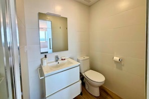 Een compacte, schone badkamer met een witte wastafel, spiegel en toilet.
