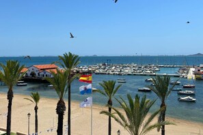 A coastal marina with boats, a flag, and palm trees. - Casa Playa de la Concha by Rental Hero (Alcazares, Los)