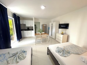 A hotel room with two beds, a TV, a desk, and a kitchenette. - VACATION STUDIOS and SUITES playa BAVARO (Punta Cana)