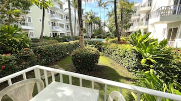 Een hotel binnenplaats met een zwembad, palmbomen en goed onderhouden hagen.