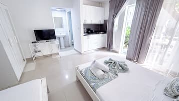 Een moderne hotelkamer met een bed, een televisie, een kitchenette en een badkamer.