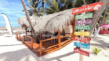 A beachside structure with a thatched roof, wooden deck, and multiple seating areas.