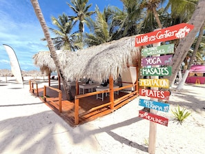 A beachside structure with a thatched roof, wooden deck, and multiple seating areas. - VACATION STUDIOS and SUITES playa BAVARO (Punta Cana)