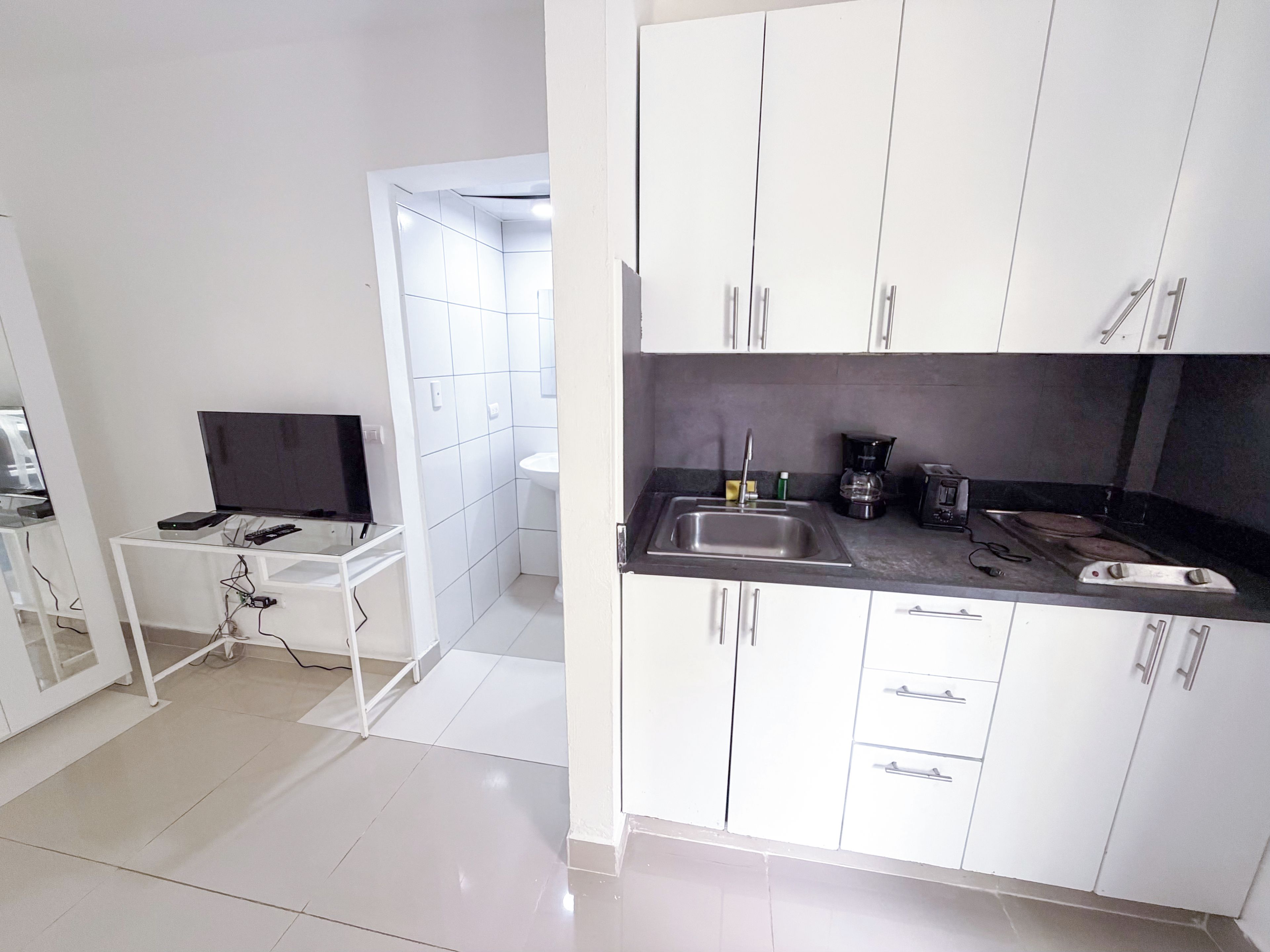 Una cocina moderna con armarios blancos, encimera negra y pileta integrada.
