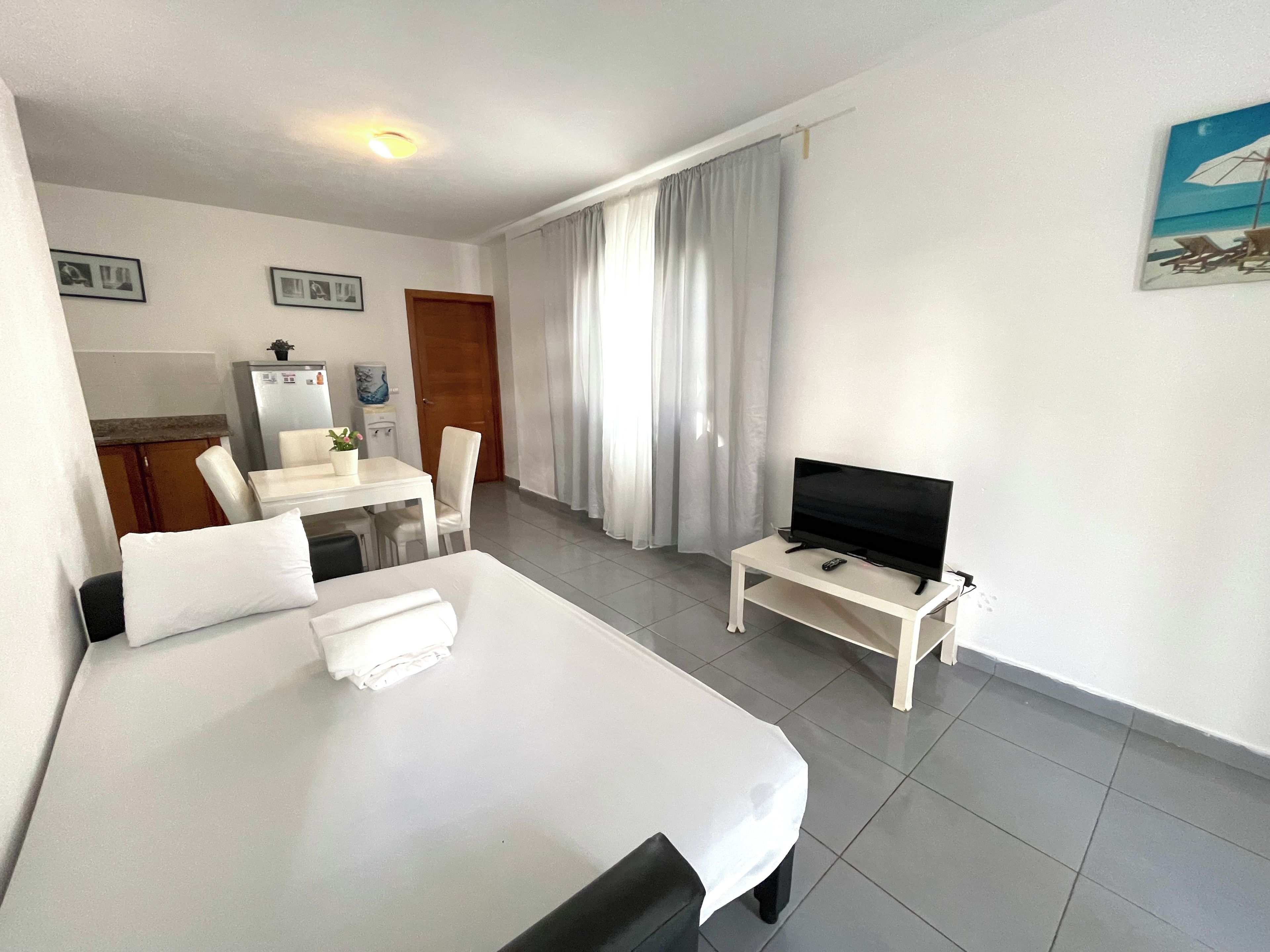 A hotel room with a bed, a desk, a chair, a television, and a painting on the wall.