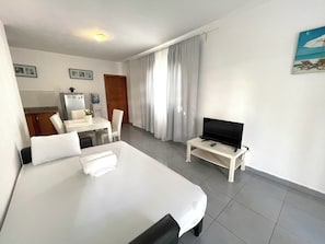 A hotel room with a bed, a desk, a chair, a television, and a painting on the wall. - VACATION STUDIOS and SUITES playa BAVARO (Punta Cana)