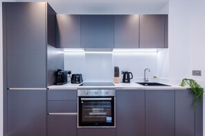 A modern kitchen with a built-in oven, a coffee maker, a toaster, and a sink. - City Centre Flat with a Terrace (West Yorkshire)