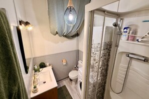 Une salle de bain comprenant un lavabo, des toilettes et un espace douche.