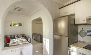 A modern kitchen with stainless steel appliances, a dining area with a table set for four, and a sofa in the background. - Relaxation on the Costa Calida (Alcazares, Los)