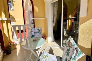A glass table with chairs, a white balustrade, and a view of a balcony with a railing. - Casa Pool Paradise by Rental Hero (Alcazares, Los)
