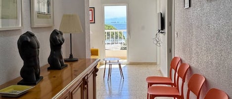 A hotel room with a wooden desk, two chairs, a lamp, and artwork on the walls.