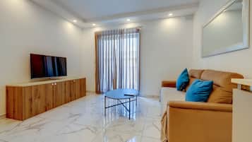Una sala de estar moderna con un televisor de pantalla plana, un mueble de madera, una mesa azul, un sofá marrón con cojines azules y un ventanal con cortinas.