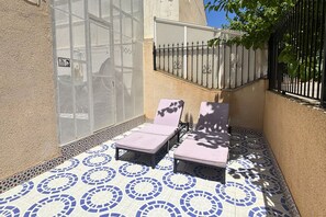 A sunlit outdoor area with two lounge chairs and a patterned tiled floor. - Casa Caroli by Rental Hero (Narejos, Los)