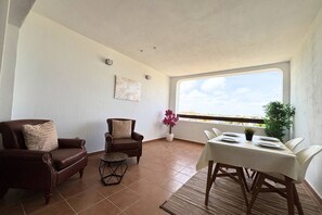 A dining area with a table set for two, a brown leather sofa, a small round table, and a potted plant. - Casa Elkie by Rental Hero (Torre Pacheco)