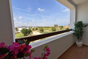 A balcony with a view of a rural landscape, a potted plant, and a flower arrangement. - Casa Elkie by Rental Hero (Torre Pacheco)