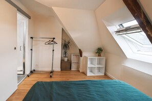 A room with a skylight, a bed, a plant, and a white shelving unit. - Le Cocon du Bel Air - 500m de la Plage (Saint-Malo)
