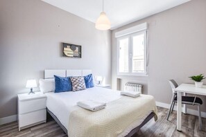 Ein modernes Schlafzimmer mit einem Bett, Nachttischen, einem Schreibtisch und einem Fenster.