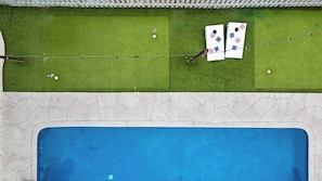 A swimming pool with a stone border and a grassy area with two American flag-themed targets. - Heated Pool, Hot Tub,Theater, Fire Pit, Mini Golf (Seminole)