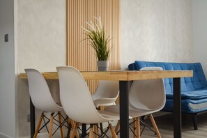 A dining area with a wooden table, white chairs, a blue sofa, and a potted plant. - Renovated apartment near Gran Vía (Madrid)