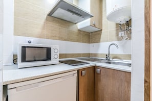 A compact kitchen with a microwave, a sink, and wooden cabinets. - Apartment near Plaza de Espana, Madrid (Madrid)