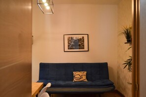 A room with a dark blue sofa, a framed picture on the wall, and a small table with a white object on it. - Apartment near Plaza de Espana, Madrid (Madrid)