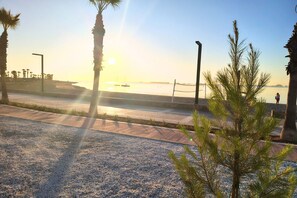 A coastal walkway with palm trees, a clear sky, and a sunset. - Casa Cisne by Rental Hero (Alcazares, Los)