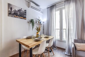 A dining area with a wooden table, white chairs, and a cityscape painting on the wall. - Penthouse with Terrace, Plaza Espana (Madrid)