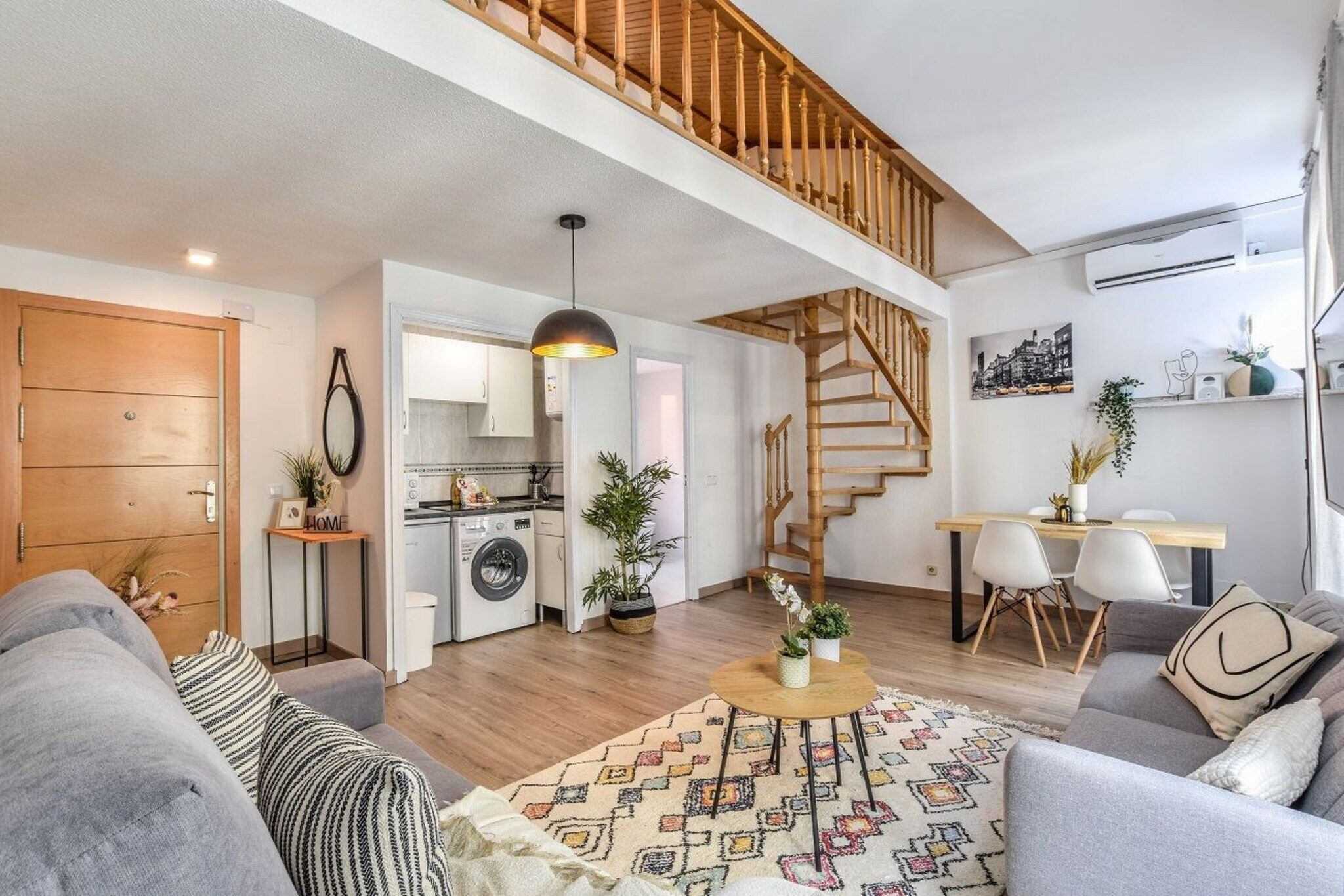 Un apartamento moderno con sala de estar, cocina y una escalera que conduce a un piso superior.