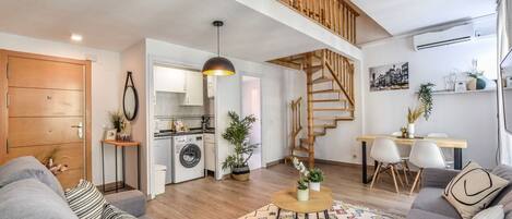 Un apartamento moderno con sala de estar, cocina y una escalera que conduce a un piso superior.