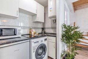 A compact kitchen with a microwave, a washing machine, and a sink. - Penthouse with Terrace, Plaza Espana (Madrid)