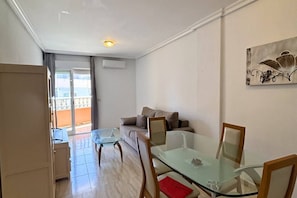 A living area with a glass table, a sofa, and a balcony with a view. - Casa Playa Lo Pagan by Rental Hero (San Pedro Del Pinatar)