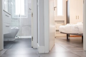Une salle de bain moderne équipée de toilettes, d’une douche et d’un espace douche séparé par des parois en verre.