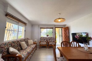 A living room with a sofa, chairs, a dining table, and a TV. - Casa Volvoreta by Rental Hero (Alcazares, Los)