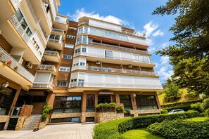 A multi-story residential building with balconies, a stone facade, and a well-maintained garden. - Spacious Madrid Apartment with Garden (Madrid)