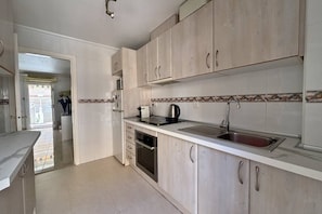 A kitchen with white cabinets, a stainless steel sink, and a built-in oven. - Casa San Juda by Rental Hero (Alcazares, Los)