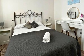 A neatly made bed with a folded towel, a desk with a chair, and a mirror on the wall. - Casa Du Viño by Rental Hero (Alcazares, Los)
