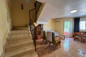 A staircase leading to a living area with a sofa, chairs, and a dining table. - Casa de la Luz by Rental Hero (Alcazares, Los)