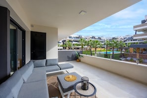 Ein Balkon mit einer Couch, einem kleinen Tisch und einem Topfpflanzen.