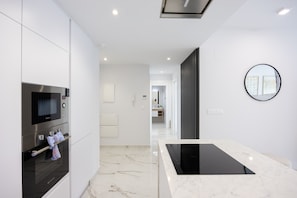 A modern kitchen with a built-in oven, a microwave, and a black induction cooktop. - Calma - Your Mediterranean retreat (Orihuela Costa)